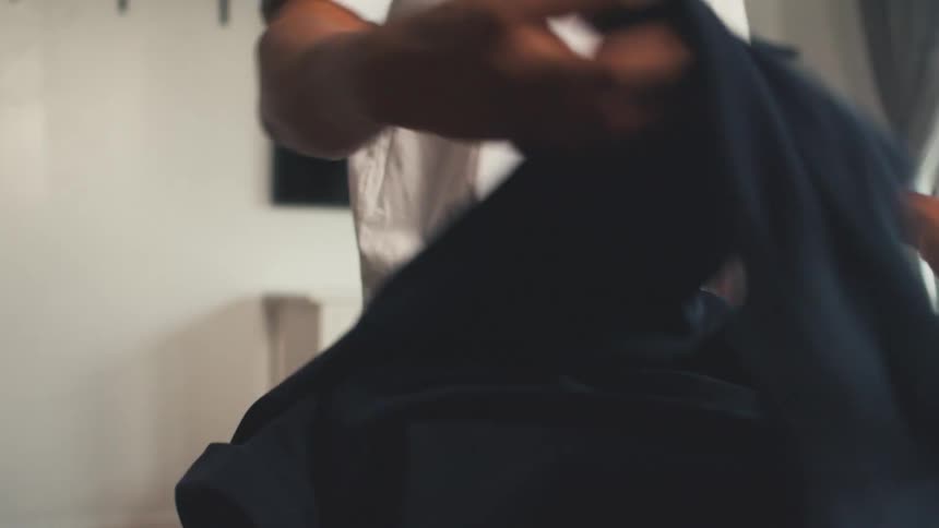 Man prepares to iron his shirt on an ironing board