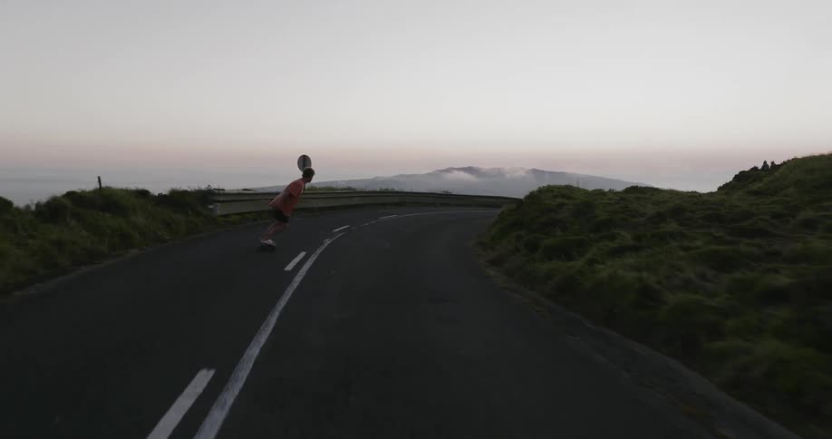 A teenage male skateboards down a rural highway
