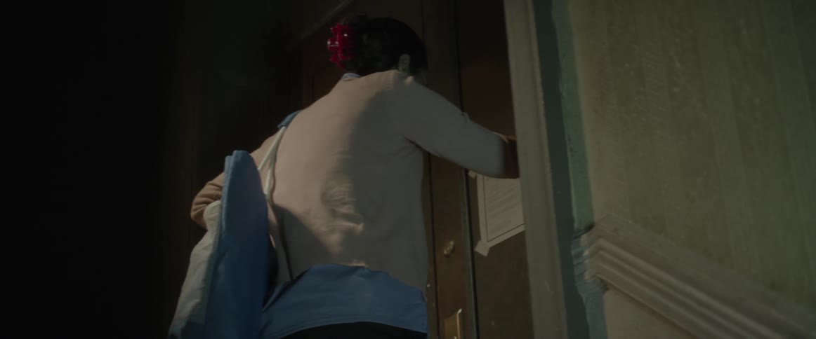 A woman finding a notice on her door leans her head on the door
