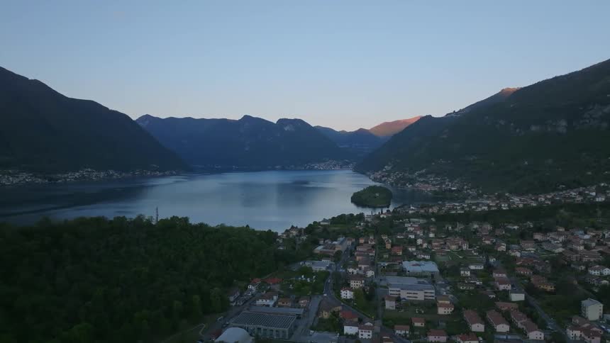 Urban city surrounded by mountains and on the edge of a lake seen on a blue sky morning