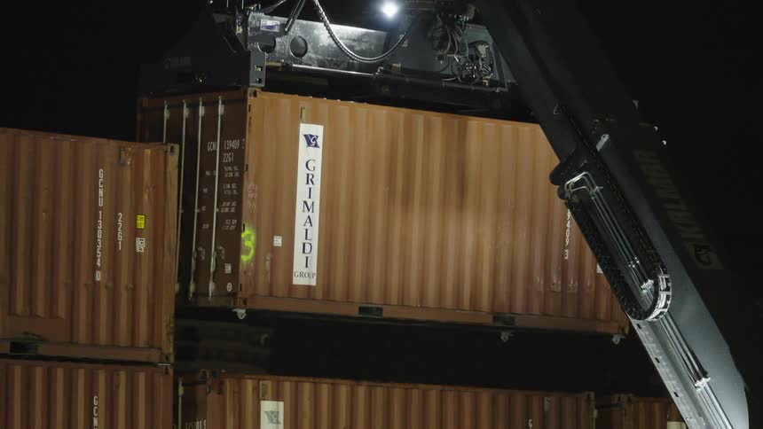 A crane lifting a shipping container at night