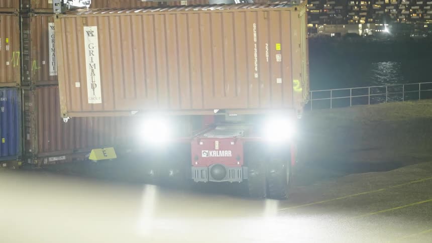 Forklift moves a shipping container on the loading dock at night