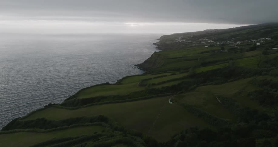 Aerial scene of green colored mountains with vegetation by the sea on a cloudy day