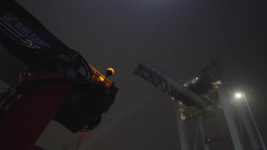 A low angle view of a large construction crane against a dark and foggy night