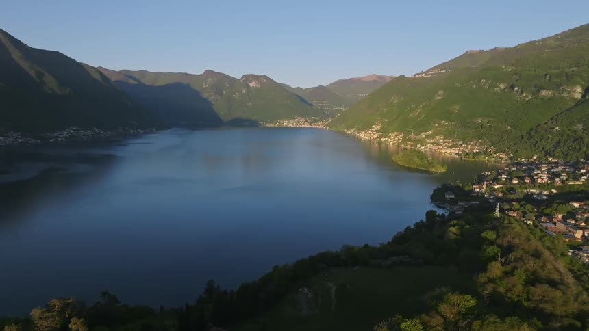 Aerial shot of a lake surrounded by mountains and a community in the background