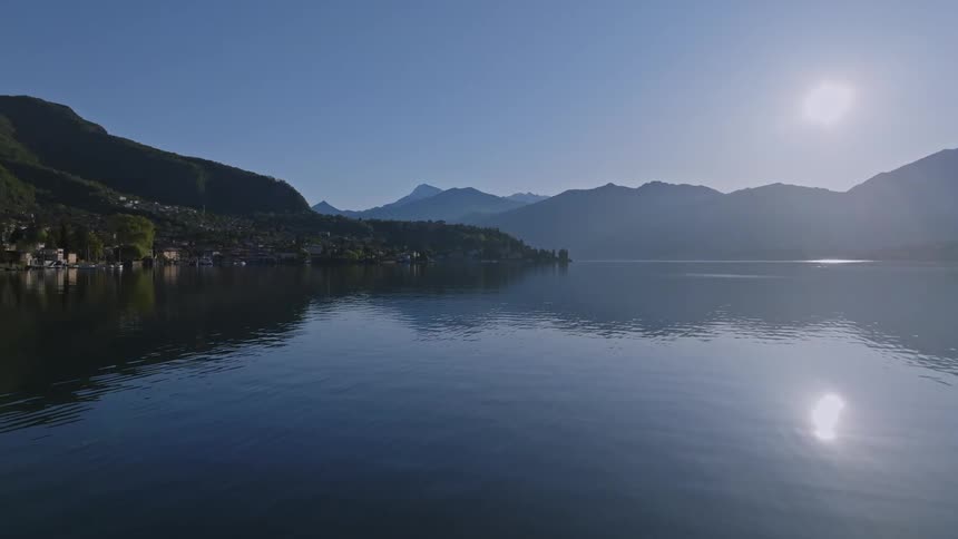 A calm lake reflects a clear blue sky and distant mountains