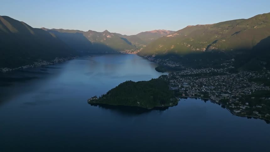 Aerial landscape of a lake surrounded by mountains and a city in the background