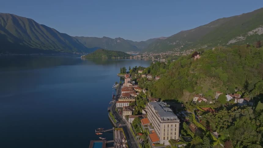 Landscape of buildings at the foot of forested mountains and by the sea
