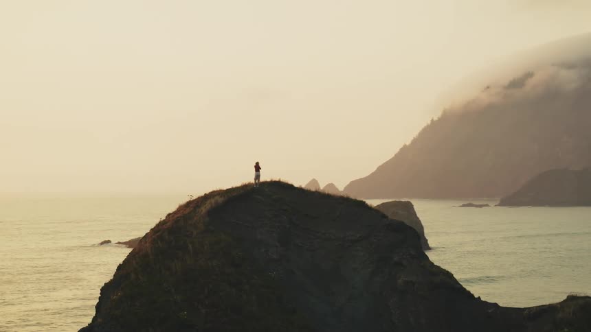 A woman walks by the cliff on the shore