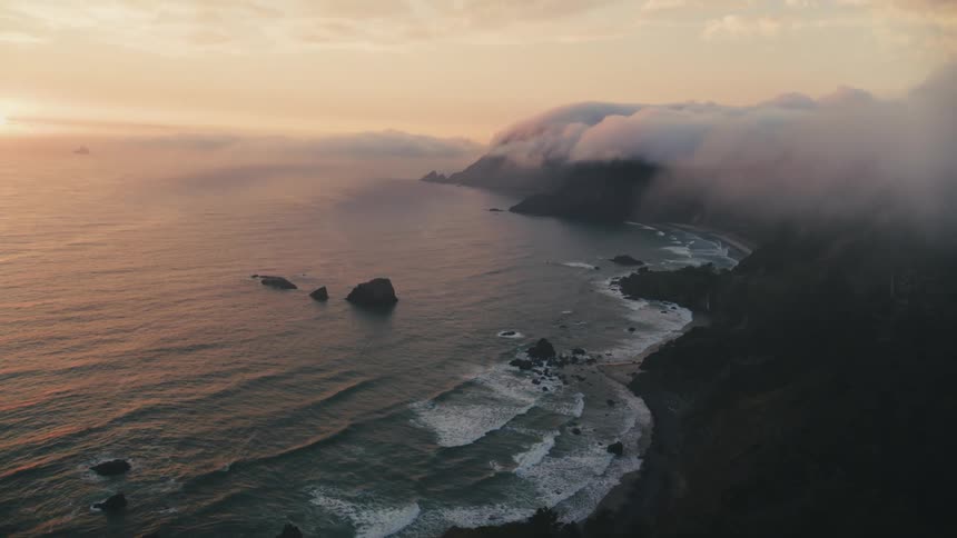 Rising sun shines onto the coast under low lying clouds