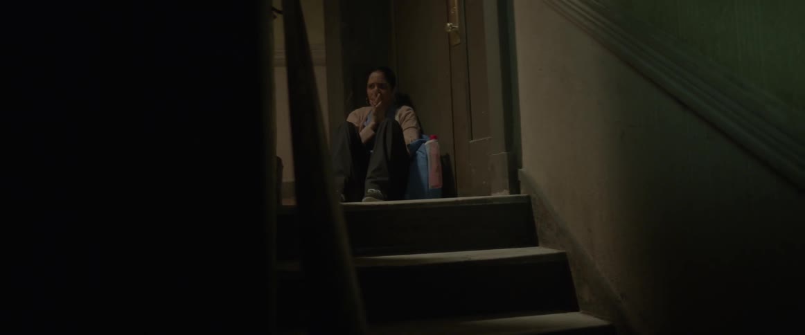 A woman is sitting by a door seemingly overwhelmed