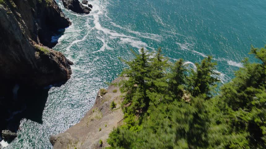 A mountainous coast gives way to ocean waves crash against cliffs