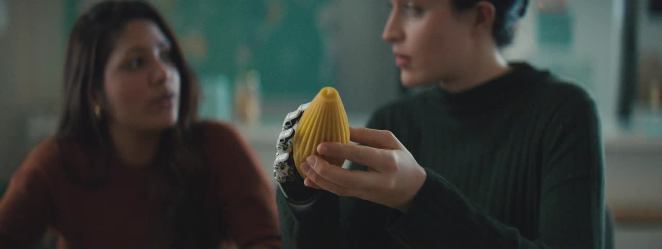 Two women engaged in conversation with one holding a yellow object while the other looks on attentively