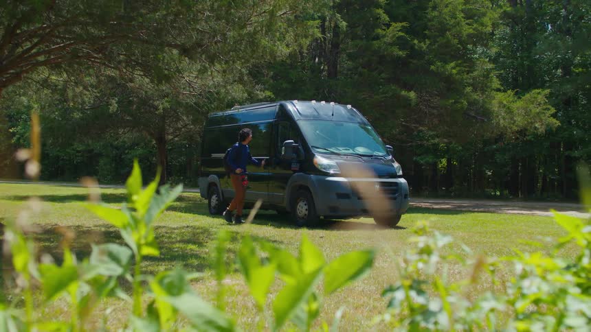 A man gets out of the van to go for a hike