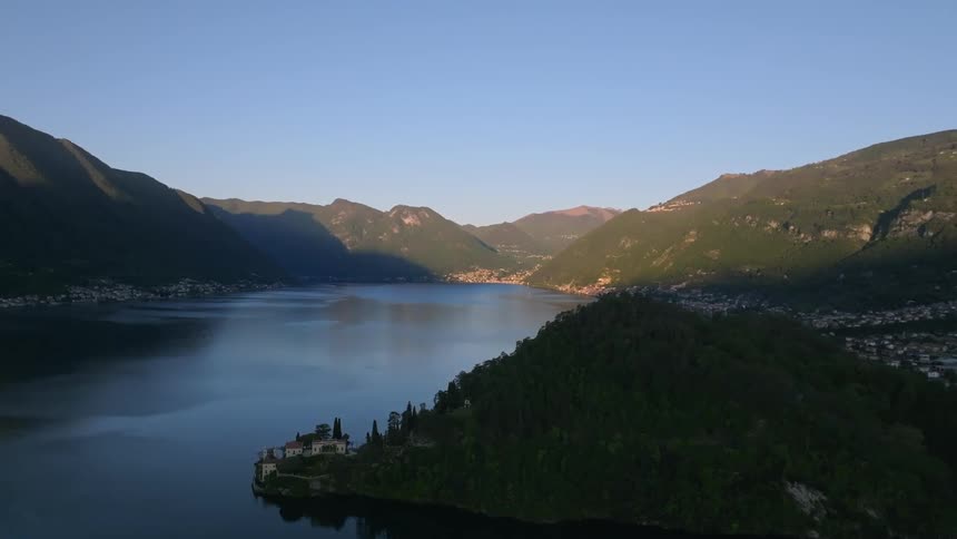 Aerial landscape of a calm lake surrounded by mountains in a city or background against a blue sky