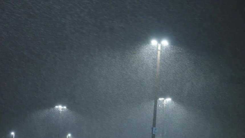 Rain falling on streetlights at night
