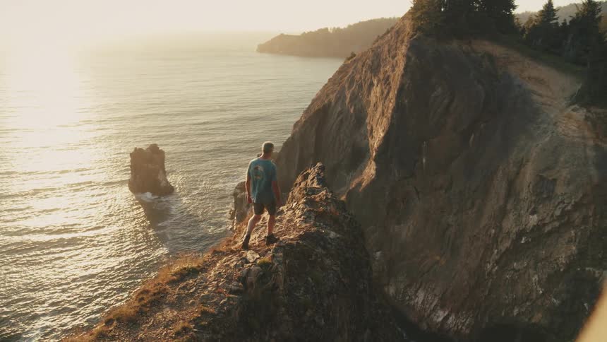 Man walking on a mountain cliff by the sea