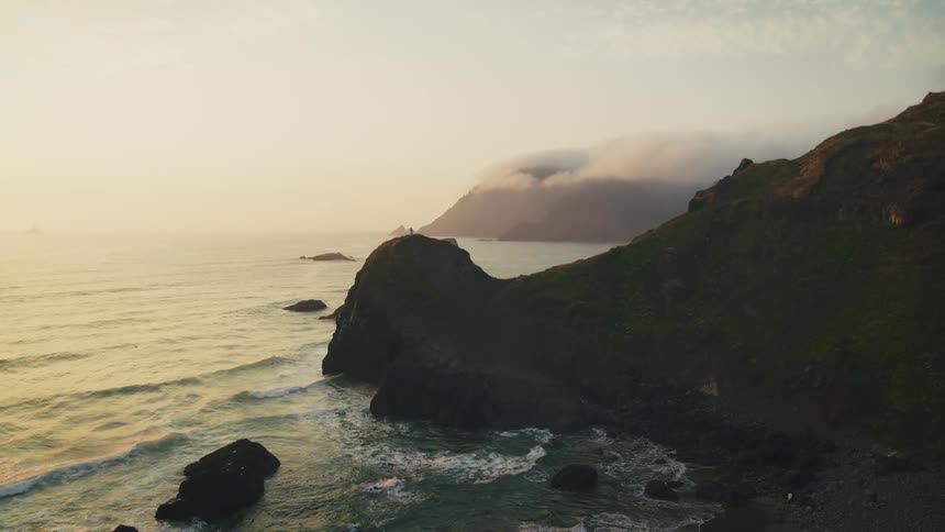 A solitary figure stands on a rocky promontory overlooking a vast ocean