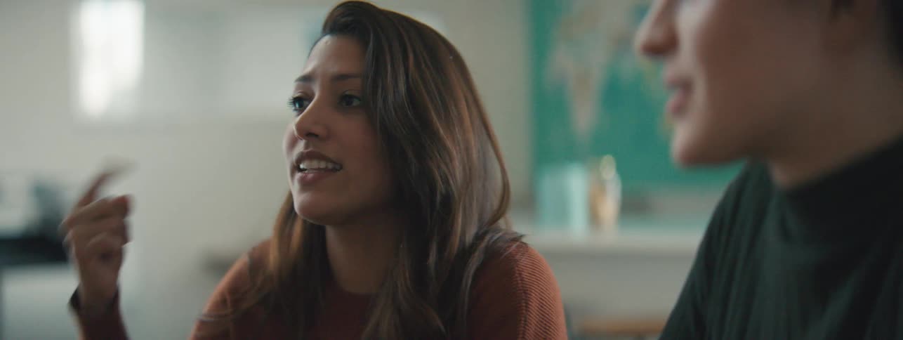 Close up of a woman explaining something to coworkers on a well lit office