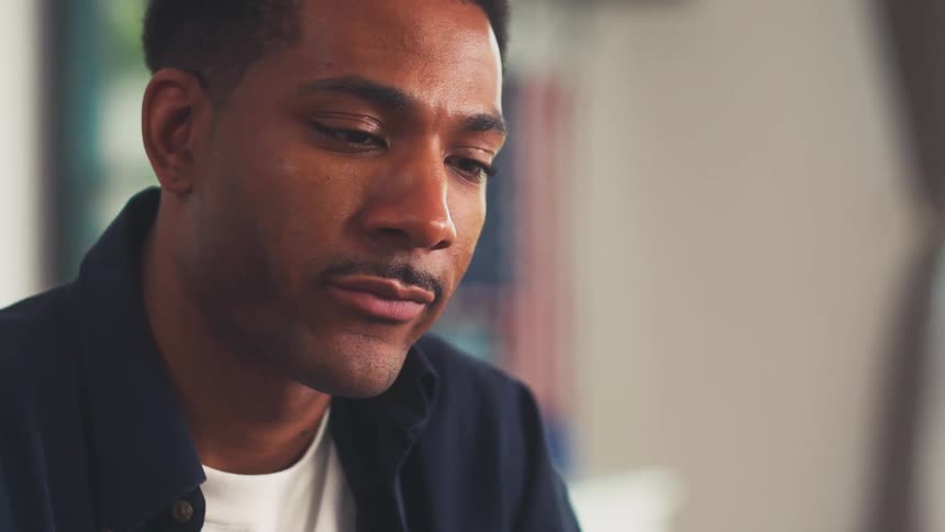 Close up of the face of a man with a thin mustache working on a well lit office