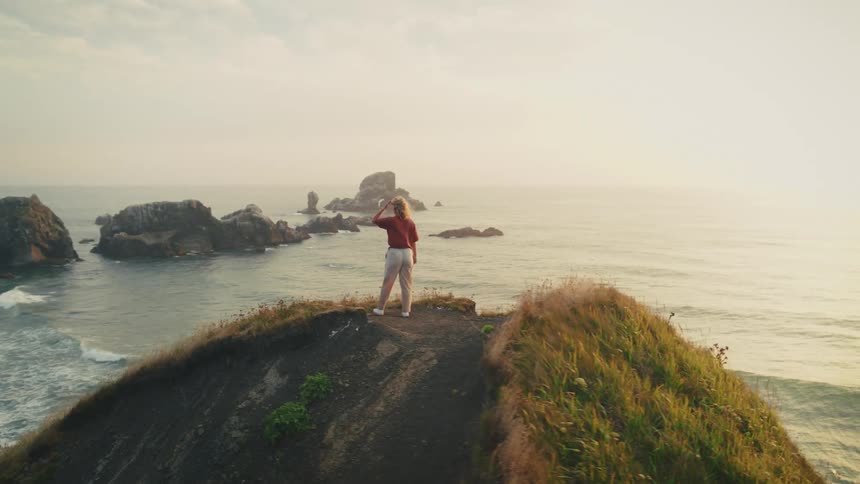 Blonde woman walking on a hill by the sea