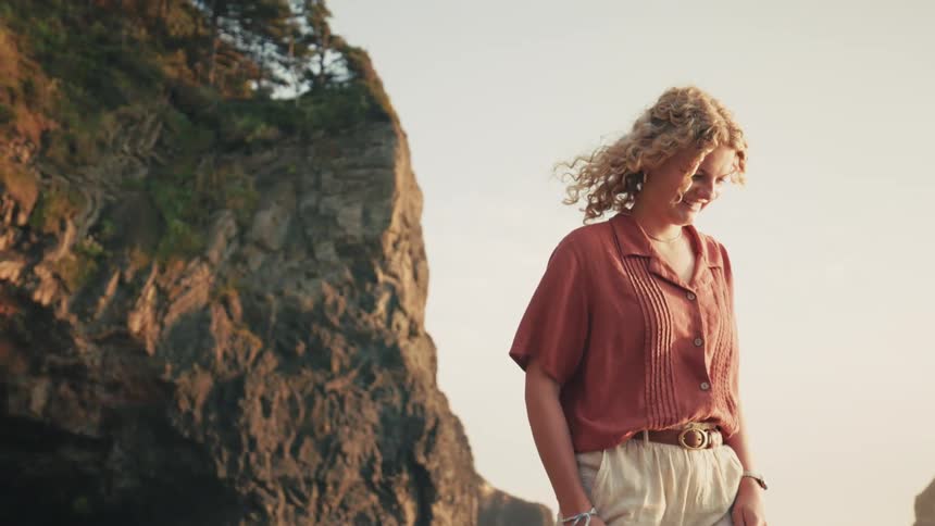 Blonde woman with curly hair walking on the beach