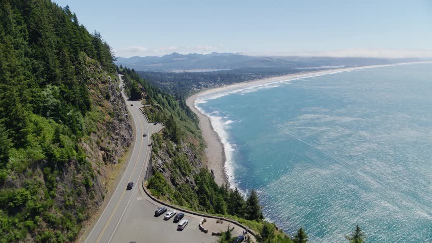 Aerial view of a highway on the edge of a mountain with a beach next to it