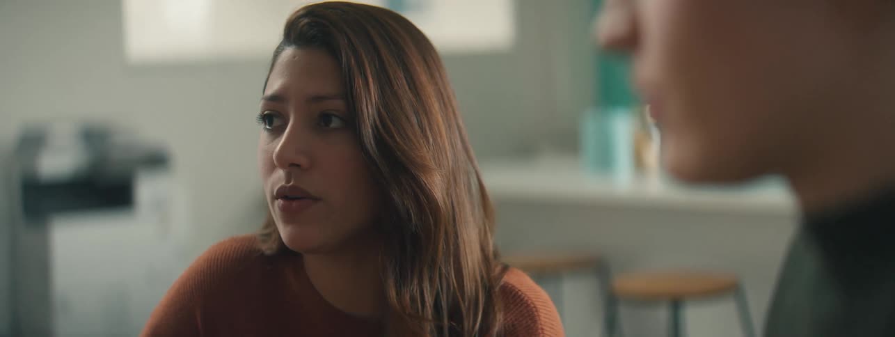 Close up of a woman explaining something to coworkers on a dimly lit office
