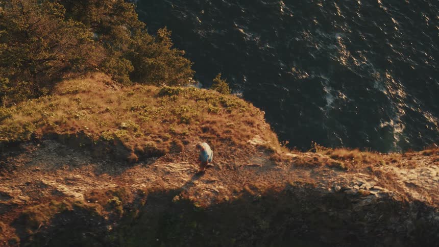 Man walking on a cliff by the sea