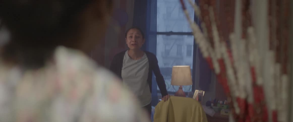 A woman opens her front door and steps backwards as a policeman walks in an handcuffs her as her daughter yells and cries