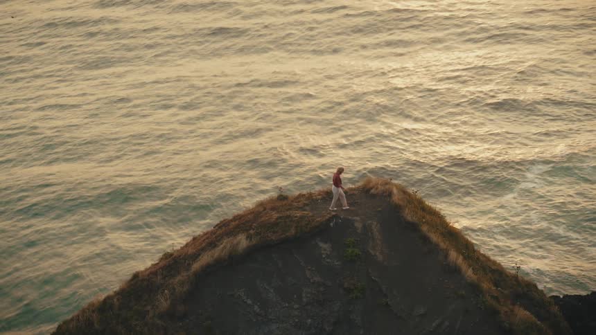 A person walks on the tall hill on the shore