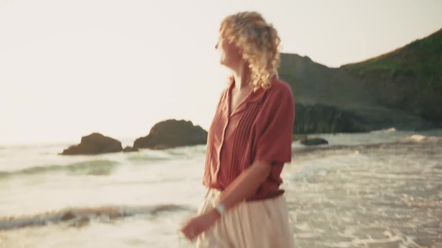 Cheerful blonde woman walking along the waters edge on the beach