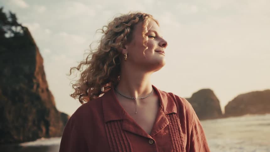 Close up of the face of a young woman turning to see the sunset over the ocean