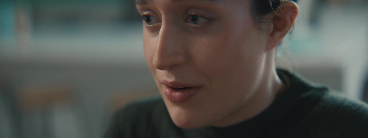 A young white woman speaks and smiles while in a room