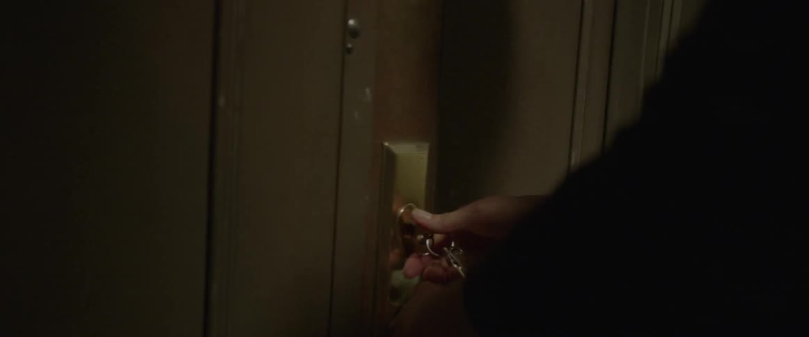 A person unlocks a door with their key
