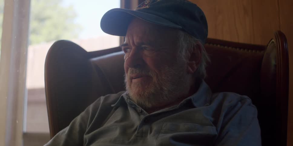 Elderly man sitting in an armchair and holding a tablet with his hands