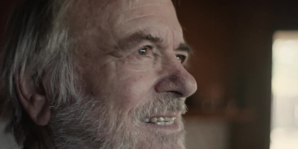 An elderly man smiling while making an expression of effort