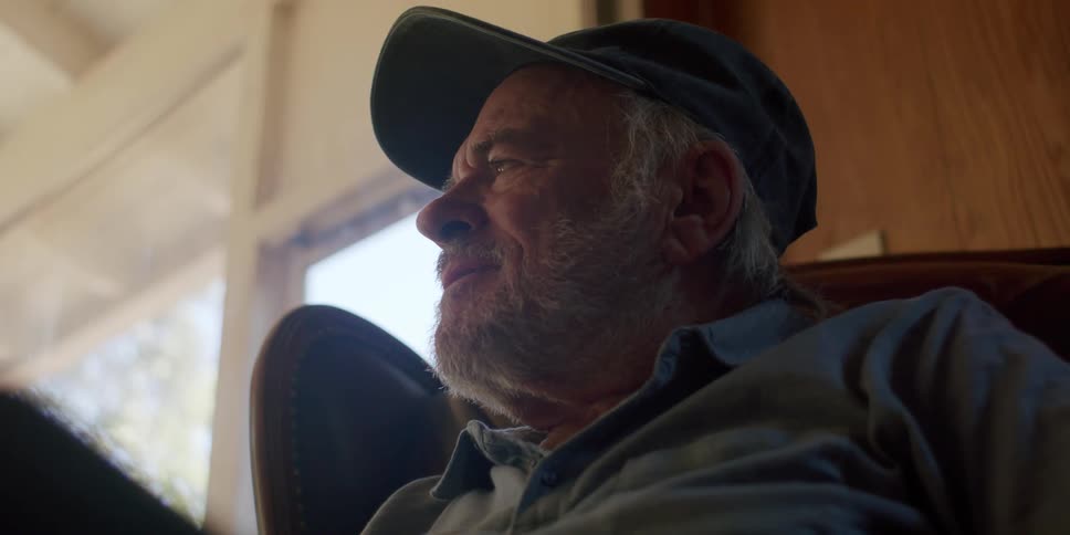 Elderly man in cap sitting in armchair and holding tablet
