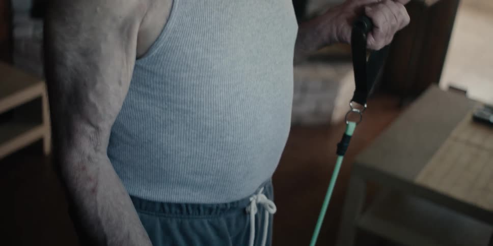 Elderly man standing stretching his arms by pulling an elastic band alternately