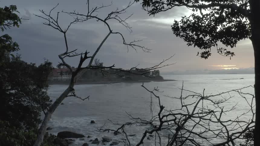 Waves roll into an ocean shore at dusk near a vacation resort