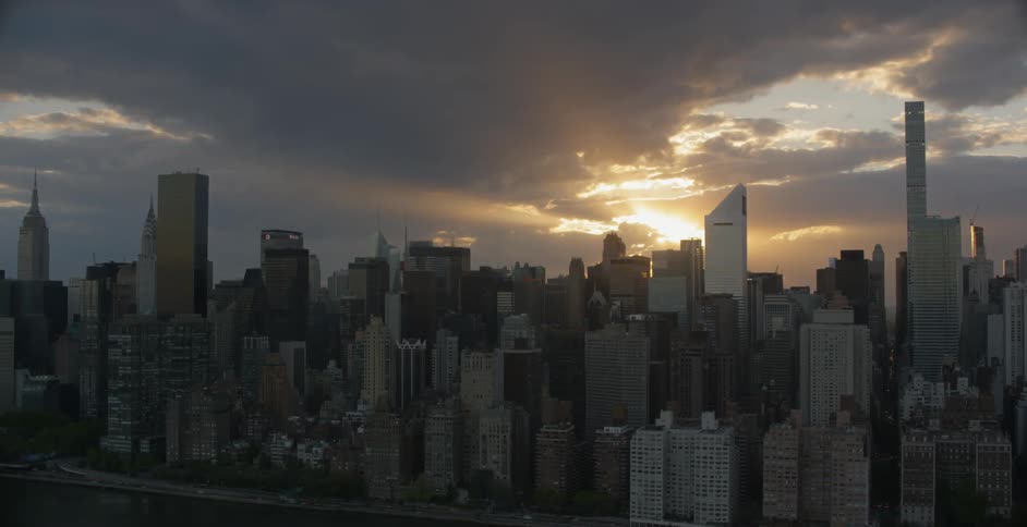 The sun is setting behind the clouds of this large city