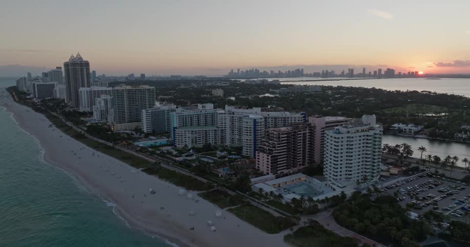 A panoramic view of miami beach at sunset featuring a long stretch of sandy beach highrise buildings and a vibrant cityscape