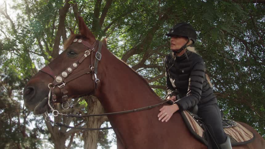 A woman leans forward and pets her horse