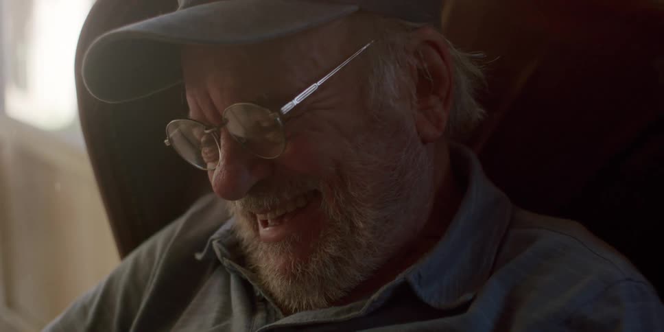 Old man sitting in an armchair laughing out loud