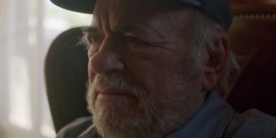Elderly man with a beard and a cap gets emotional while using a tablet