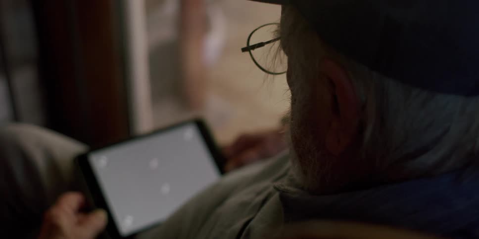 An elderly man with a tablet with a replaceable screen on his lap