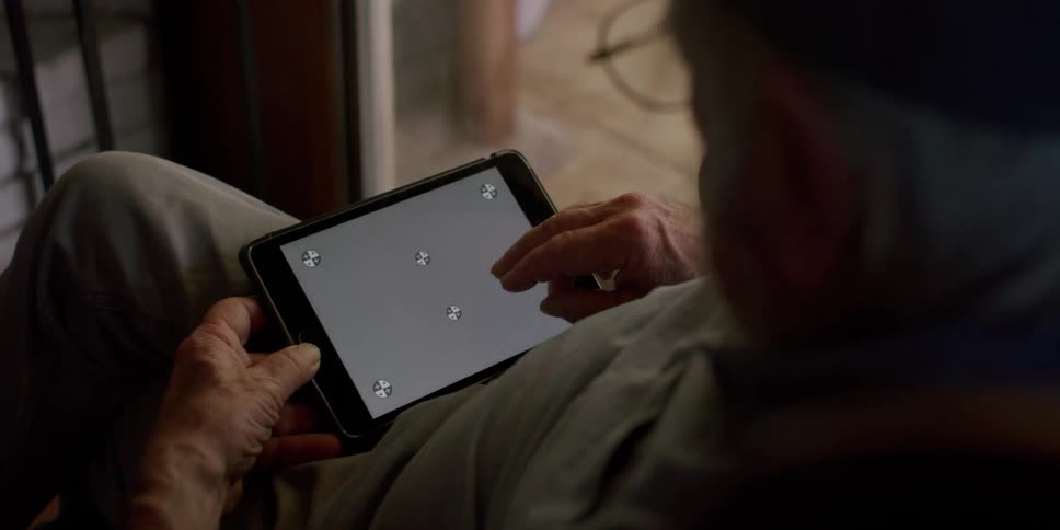 An elderly man holding a tablet with a replaceable screen on his lap