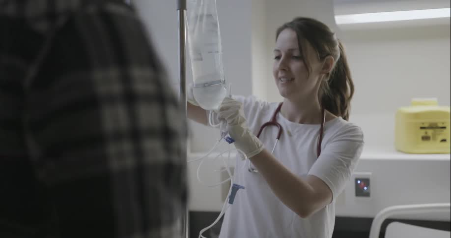A nurse is hanging an iv bag and speaking to a patient