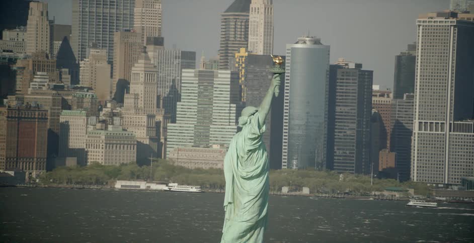 The statue of liberty sits in the water before the city