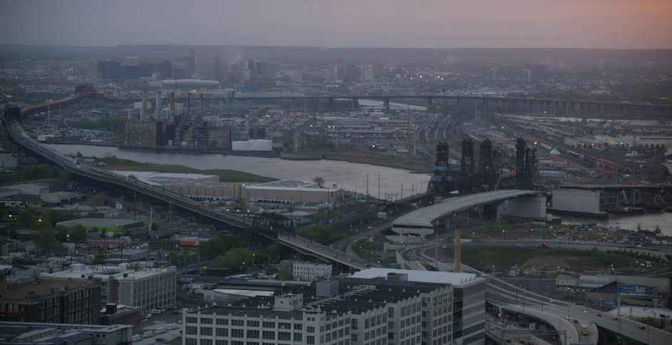 The sun sets over city buildings and roads